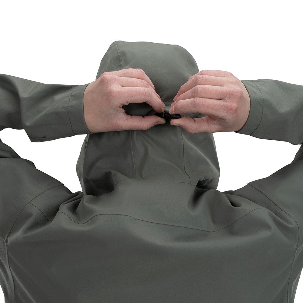 Product shot showing a person fastening the hood of a sage green waterproof jacket featuring a unique adjustable clasp and subtle seam detailing