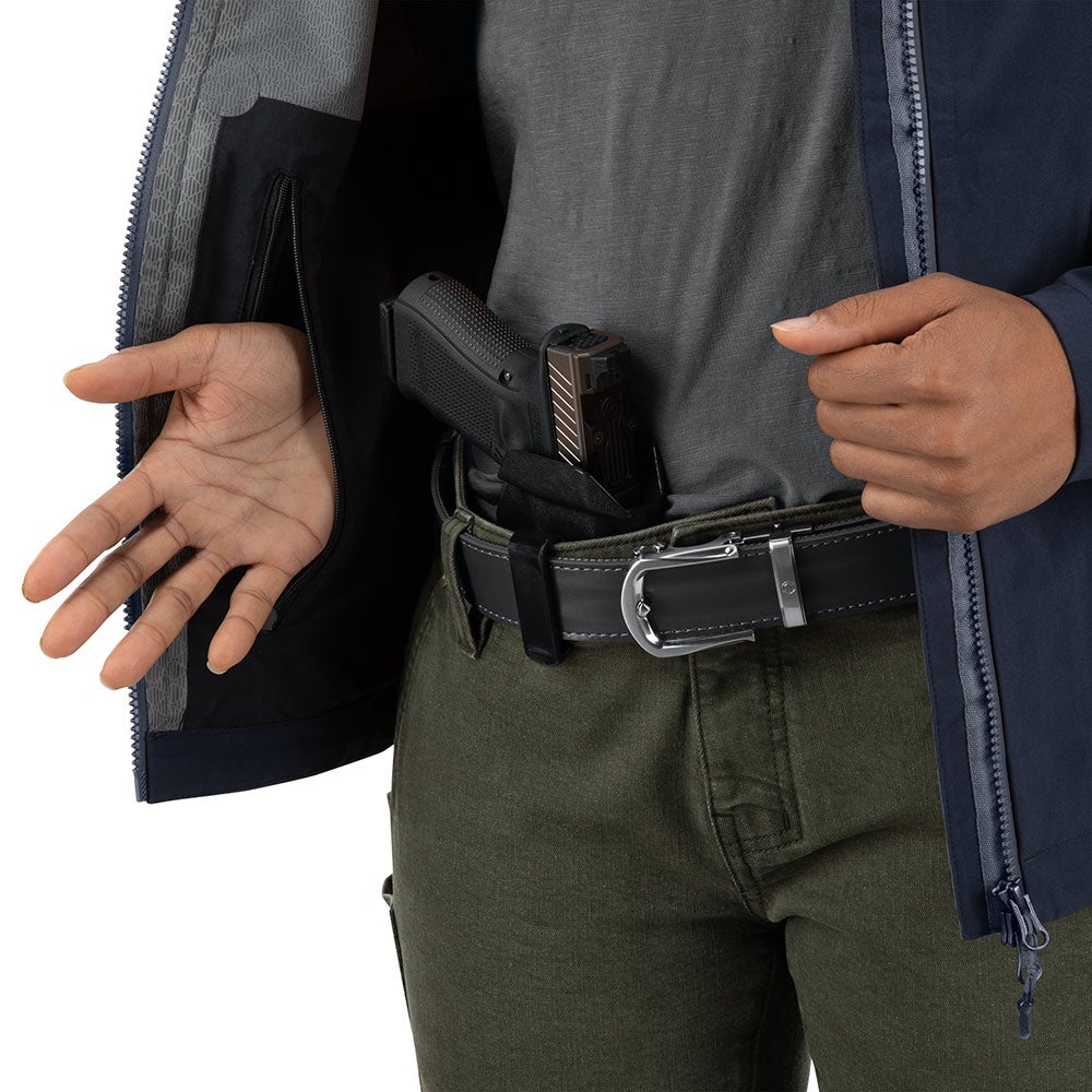 Product shot showing a person wearing a navy blue jacket with a concealed handgun in an inside pocket olive green pants and a silver buckle belt