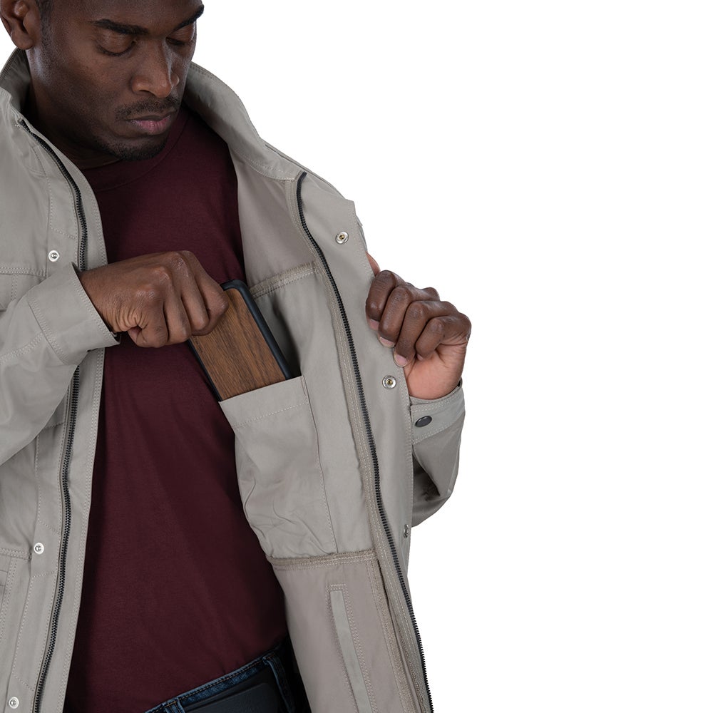 Product shot of a man in a beige jacket with multiple pockets showing a dark wooden phone case a maroon shirt and dark denim jeans