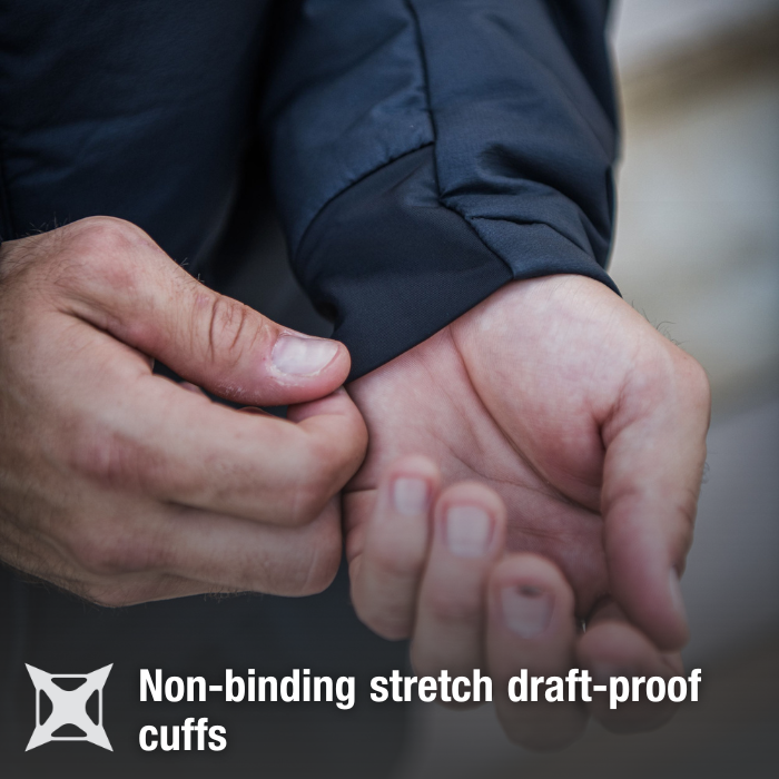 Close-up photograph showing a person's hands adjusting the non-binding stretch draft-proof cuffs of a dark navy jacket the fabric is smooth and soft the fingers are slightly tanned and the nails are neatly trimmed